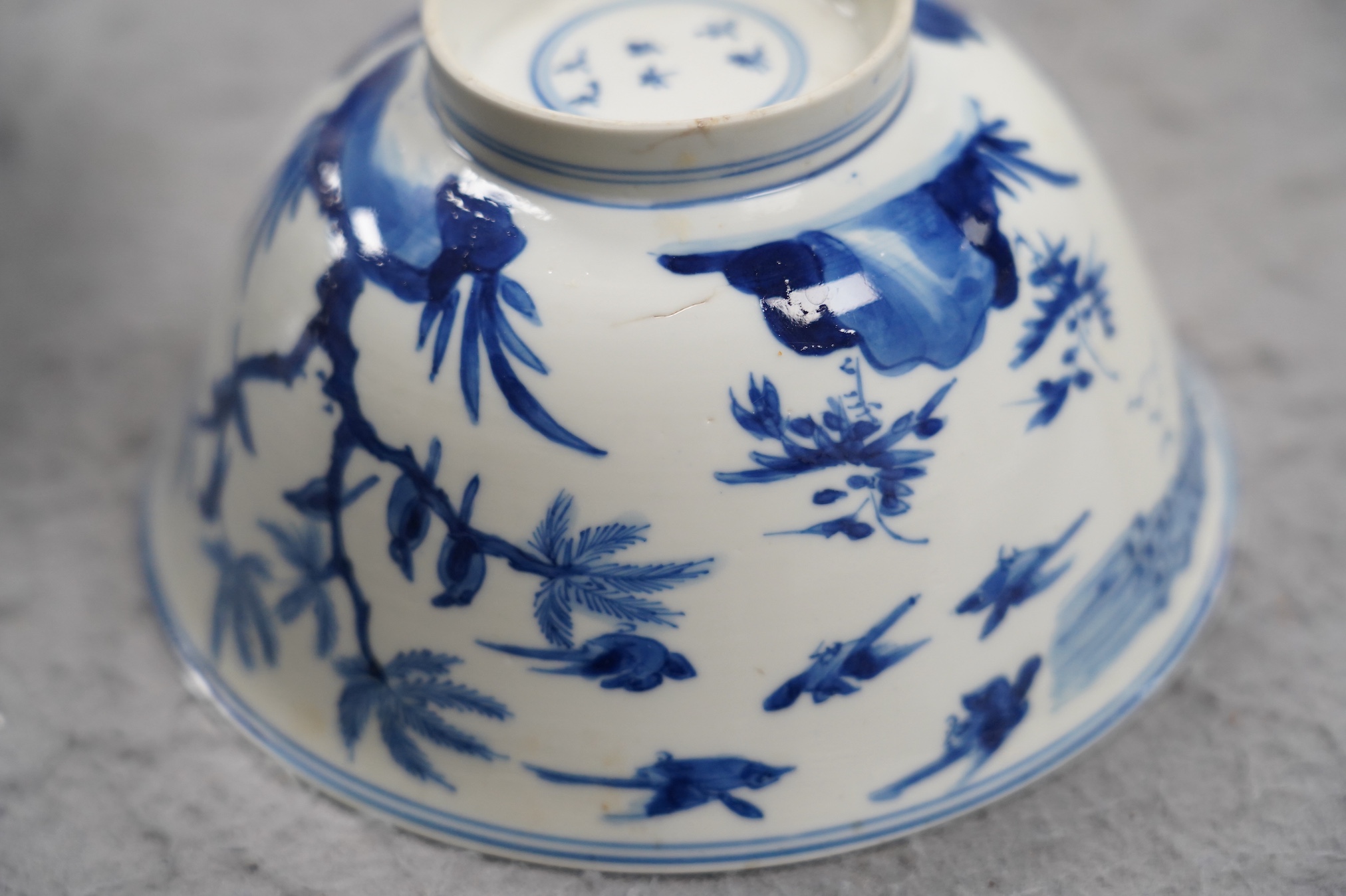A near pair of Chinese blue and white ‘birds’ bowls, Kangxi period, one bowl restored